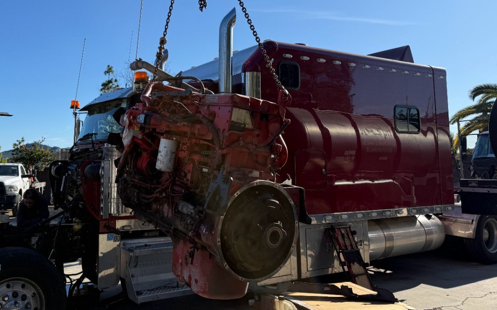 Red diesel engine lifted from a semi truck during overhaul